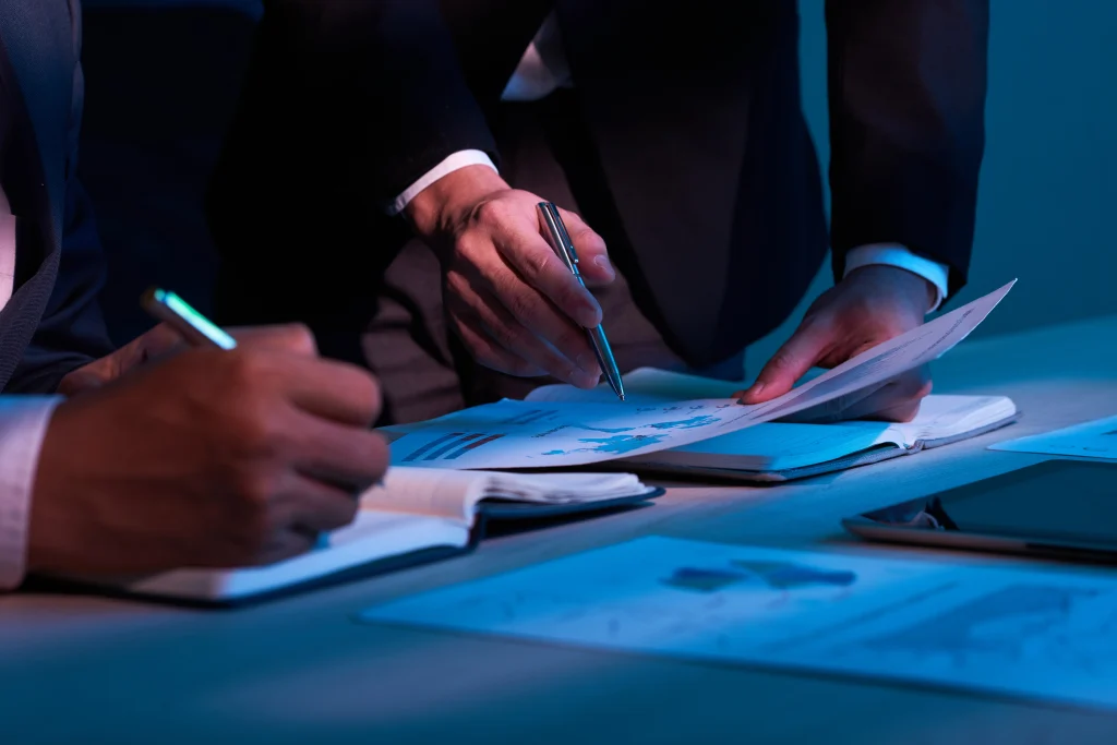 Dos personas revisando y firmando documentos impresos sobre una mesa